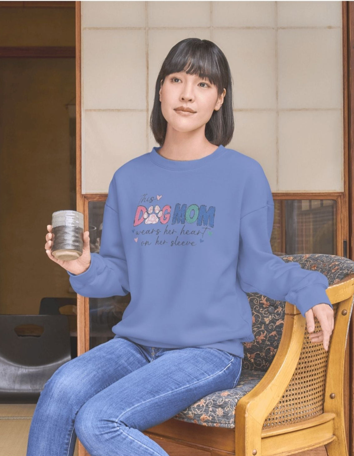 Person wearing a blue sweatshirt with colorful text, sitting in a room with wooden furniture.
