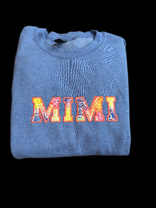 Folded blue sweatshirt with colorful text design on a woven surface