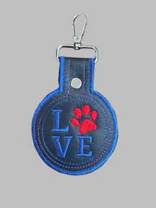 Keychain with 'LOVE' and red paw print design on a black background