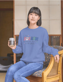 Person wearing a blue sweatshirt with colorful text, sitting in a room with wooden furniture.